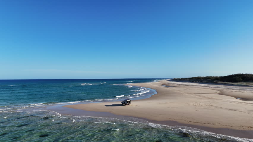 Aerial drone view of 4WD at Sandy Cape, northern tip of Fraser Island K gari, Queensland, Australia. White sand beach, turquoise water, iconic off-road travel destination.
