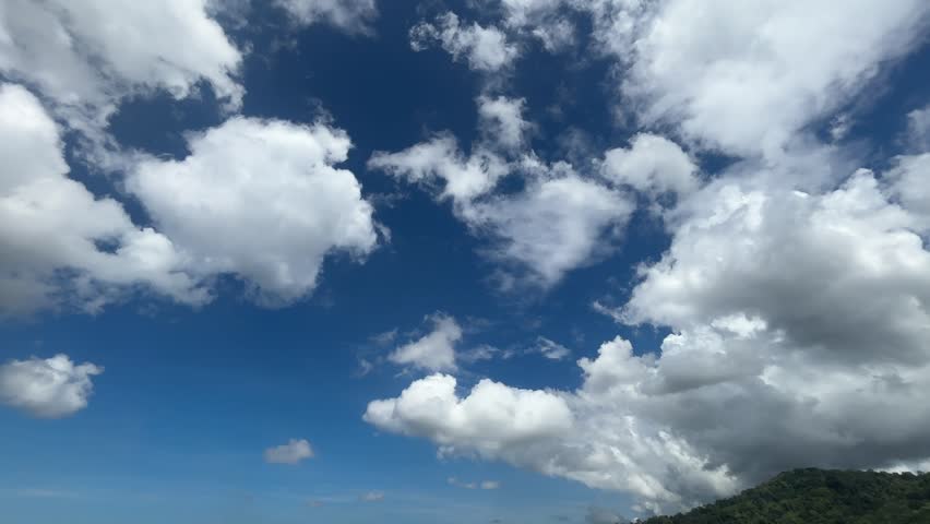 Stunning 4K blue sky with beautiful white cumulus clouds over tropical green hill