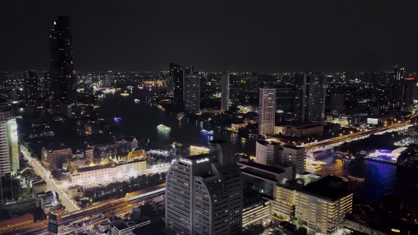 Rooftop view of Bangkok at night with illuminated skyline, boats moving along the Chao Phraya River, and vibrant city lights glowing against the dark sky.