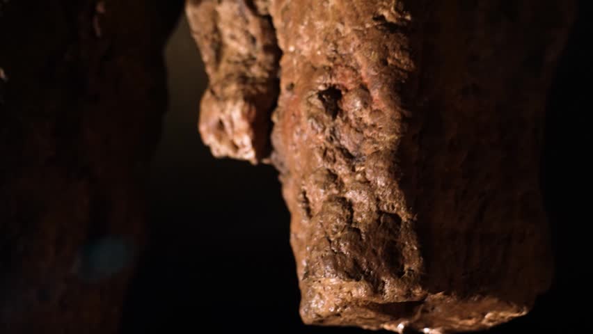 Wet stone surface and rugged cave walls in underground natural formation. Dark moist rock texture inside ancient cave in Chhattisgarh India.