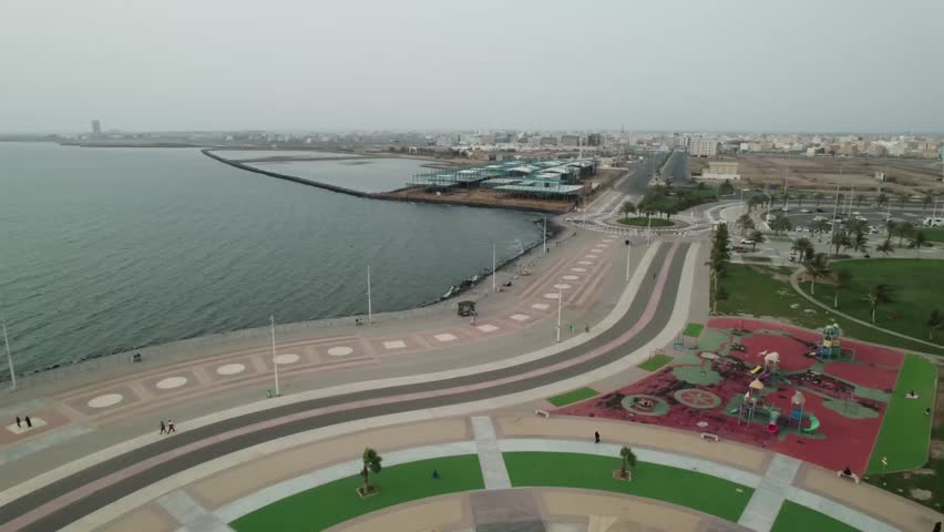 Aerial view of city waterfront promenade with playground and ocean waves