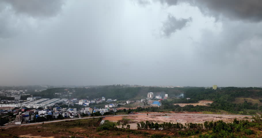 4K wide shot of a lightning strike over the landscape. High-contrast footage showing an electric discharge against dark monsoon clouds and a distant rain curtain.