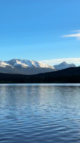 Pyramid Lake with snow capped mountains and forest reflecting in calm water in Jasper National Park, Canada