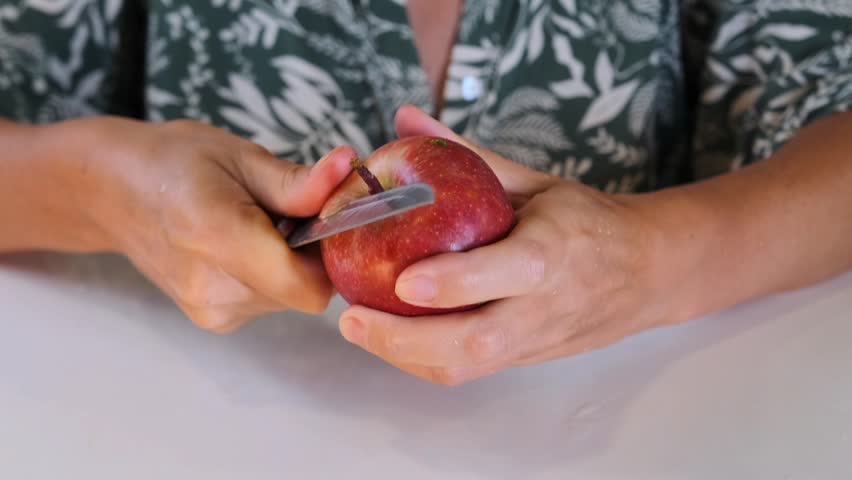 woman peeling apple front view removing skin with knife in hands, preparing fresh fruit for cooking or snack, home kitchen routine, healthy eating and daily food prep process