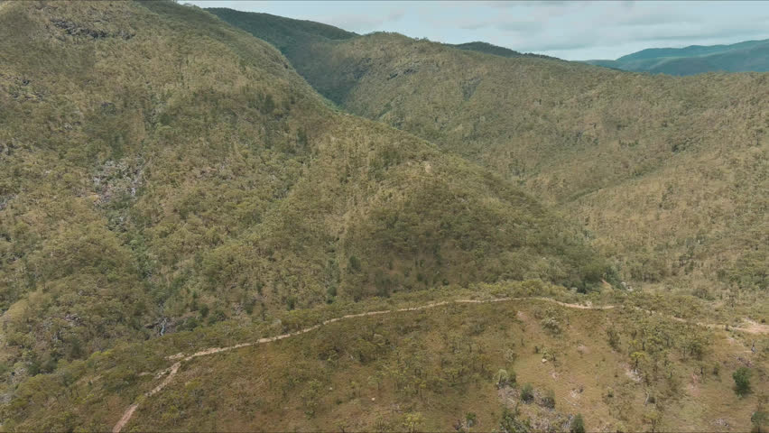 A unique aerial view of the Australian mountain ranges with a dirt road running through the hills.