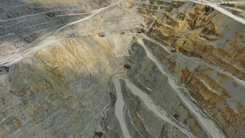 Aerial view of open pit copper ore mine and heavy mining equipment. Excavator and mining trucks in quarry, 4k