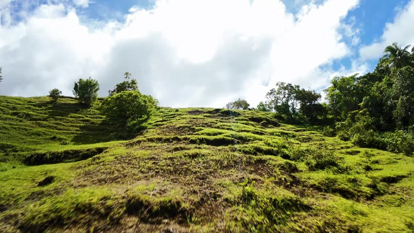 Sunlit Grassy Ridge On Siquijor With Small Lookout Hut, Vibrant Blue Sky And Dramatic Clouds, Steep Slope With Tufted Grass And Scattered Trees, Warm Sunlight Casting Contrasty Shadows,