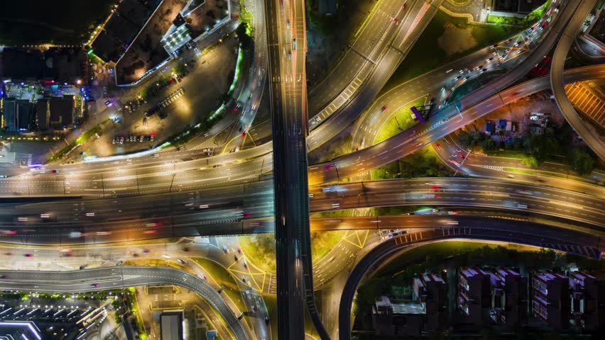 Aerial top down night timelapse of a busy highway interchange with traffic light trails in Kuala Lumpur, Malaysia. Urban road network showing dynamic city transport, infrastructure and movement.