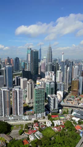 Aerial drone view of Kuala Lumpur skyline featuring modern skyscrapers, dense urban buildings and city infrastructure. Bright daytime cityscape showing rapid development in Malaysia.