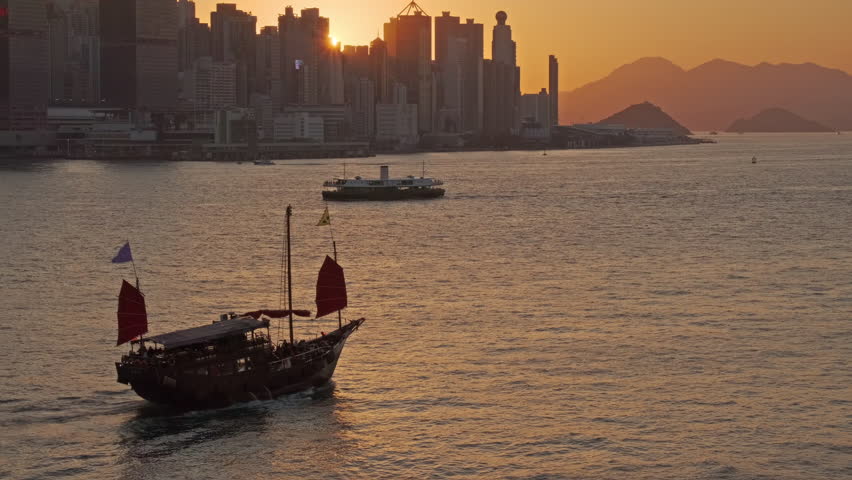 Hong Kong at sunset. Traditional Chinese Junkboat sailing in Victoria Harbour and Hong Kong Central, 4k