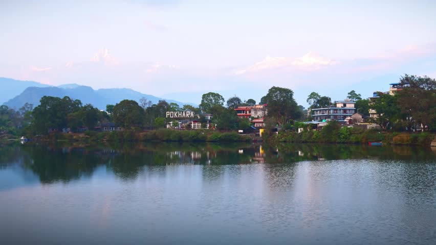 Pokhara Phewa Lake reflection Machapuchare Annapurna South Hiunchuli mountains Nepal sunrise calm water lakeside city zoom in timelapse landscape.Gandaki Province. Central Nepal.