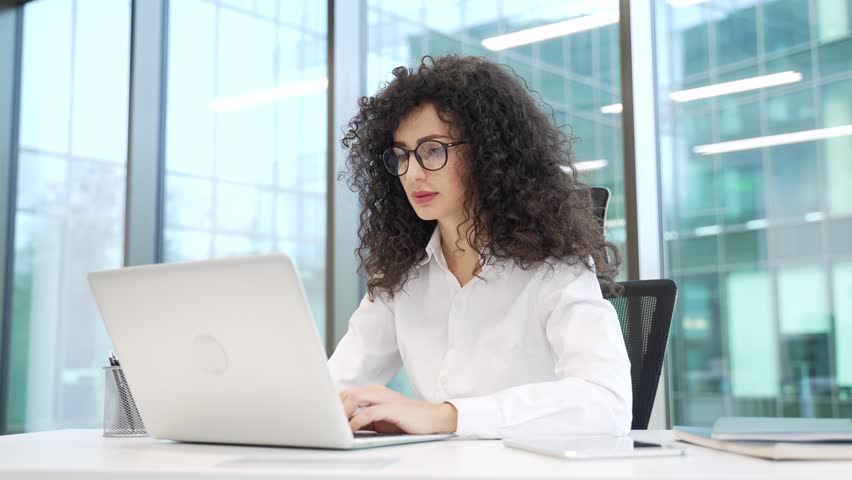 Confused businesswoman having difficulty making transaction using laptop sitting at desk at workplace in a modern business office. Frustrated female employee having problems working online on computer