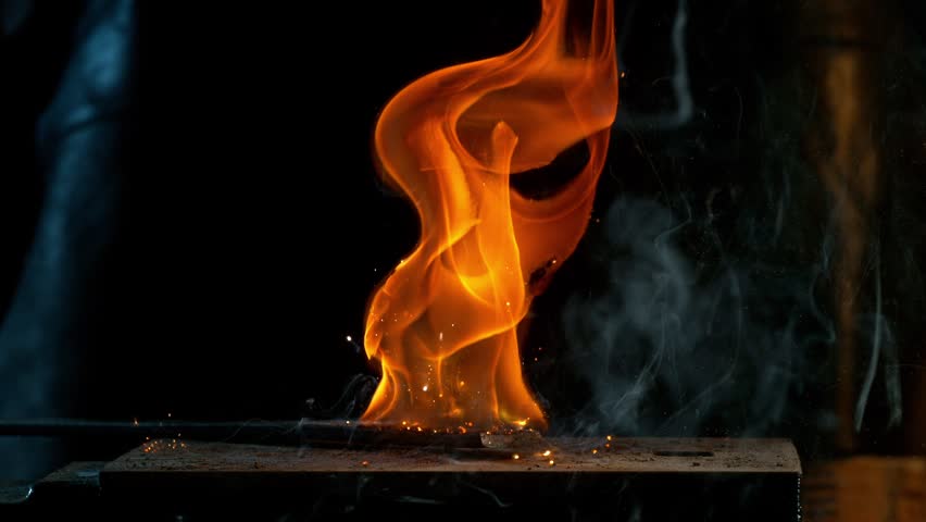 Close-up of blacksmith forging glowing hot iron on anvil with flying sparks. Super slow motion filmed on high-speed cinema camera at 1000 fps