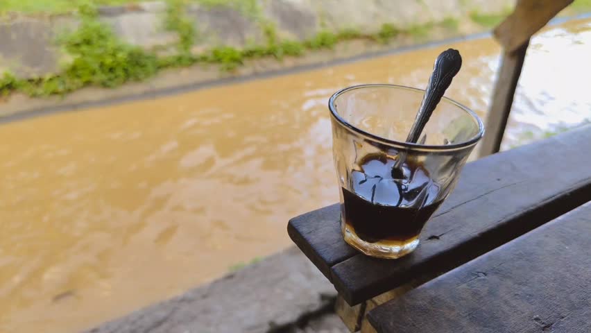 a cup of coffee on a wooden table by the river