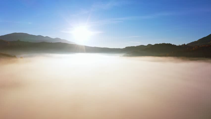 Sunrise light among clouds above mountainous canyon in mist