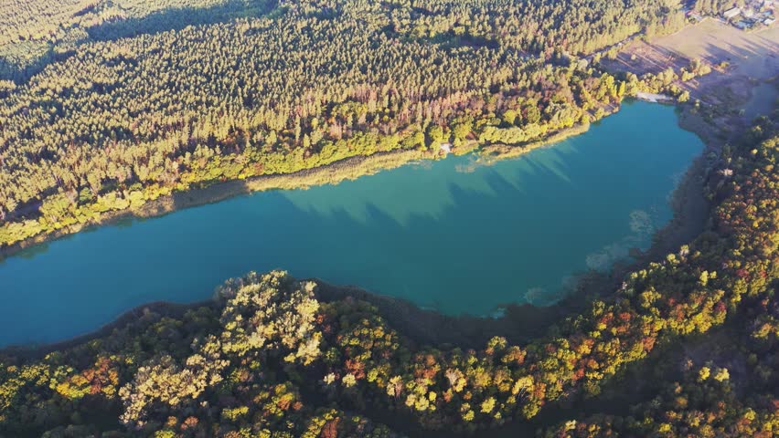 Scenic landscape of lake among lush colorful trees at sunset