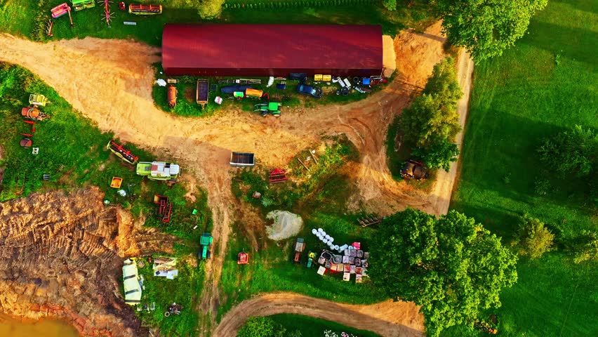Rural land with farm building, dirt roads, agricultural vehicles and tools for crop production