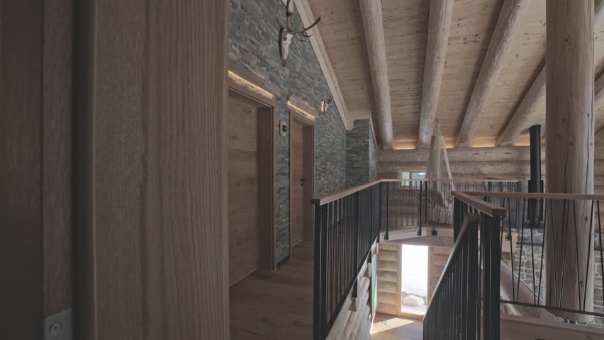 Modern and rustic interior of a mountain chalet with wood beams, stone walls, and warm lighting