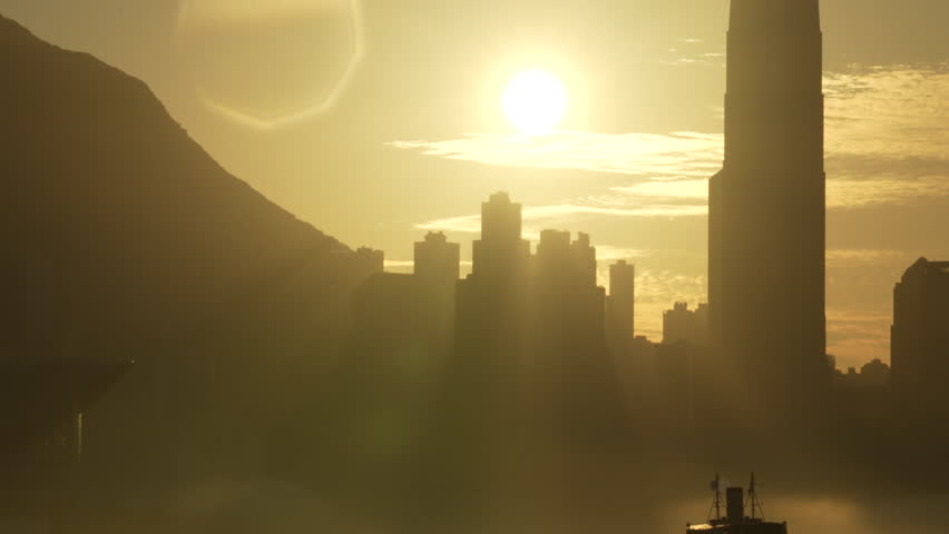 Silhouette of Hong Kong skyline under golden sunset, ferries cruising on Victoria harbour, tele lens shot, sea fog on the water.
