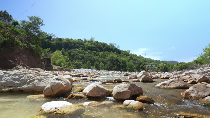 River flowing through landscape with mountains in background. Wide scenic view of water moving across natural terrain, representing nature, travel and peaceful outdoor environment.
