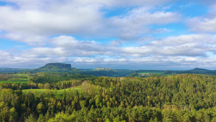 Timelapse of clouds moving over forested hills with shifting sunlight and shadows in Saxon Switzerland, Germany. Königstein Fortress and Gohrisch visible in the distance