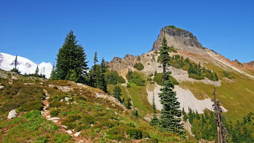 footage of the rugged landscape along the Pinnacle Peak Trail in Mount Rainier National Park, Washington. The trail winds through alpine meadows and rocky terrain, offering stunning panoramic views of