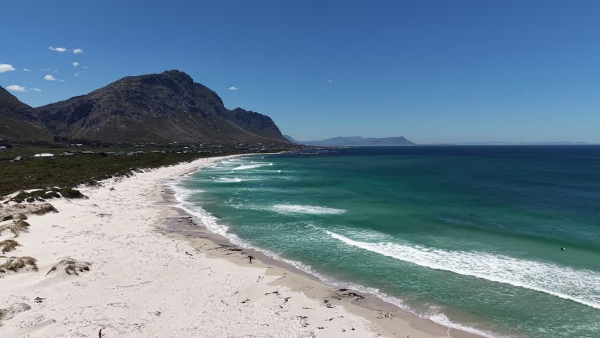 White sandy beach at Betty’s Bay, South Africa, captured by drone from above, vivid summer colors, empty coastline, wide horizon, fresh air, calm atmosphere and sense of freedom.