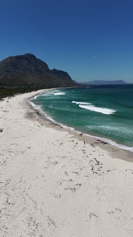 White sandy beach at Betty’s Bay, South Africa, captured by drone from above, vivid summer colors, empty coastline, wide horizon, fresh air, calm atmosphere and sense of freedom.