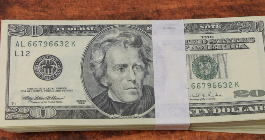 A bright rifle bullet placed on twenty dollar banknotes over a mahogany table for concepts of corruption and dirty money in global wars!