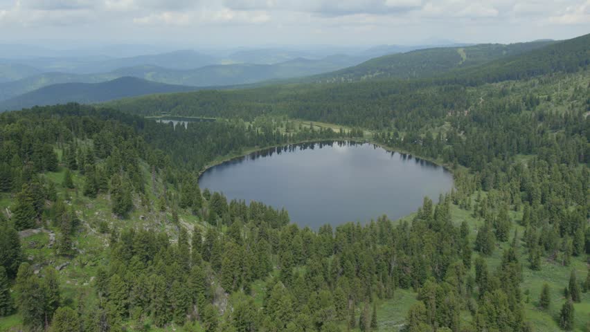 Drone footage of Karakol Lakes, a group of alpine lakes among conifer taiga and rolling ridges in Altai Republic, Russia, under cloudy summer sky