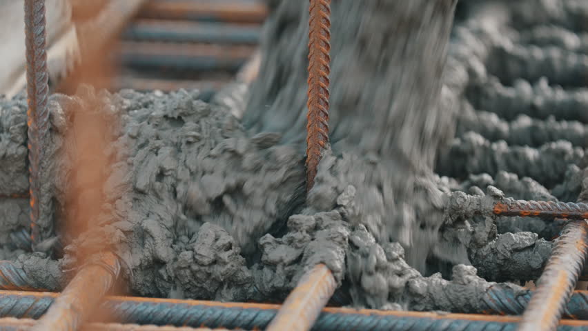 Pouring concrete mix over rebar grid during foundation construction close up