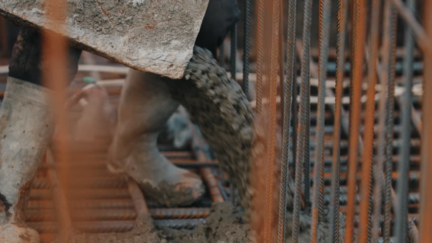 Pouring concrete mix from bucket into rebar structure during construction close up