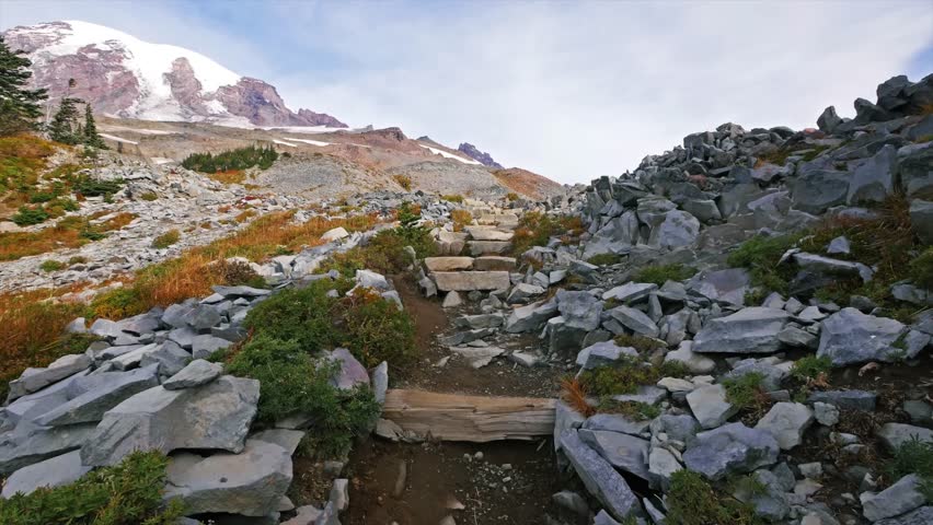 Footage of a scenic, rugged mountain trail ascending towards Panorama Point in the Paradise area of Mount Rainier National Park. The well-maintained Skyline Trail features stone steps and dirt paths,