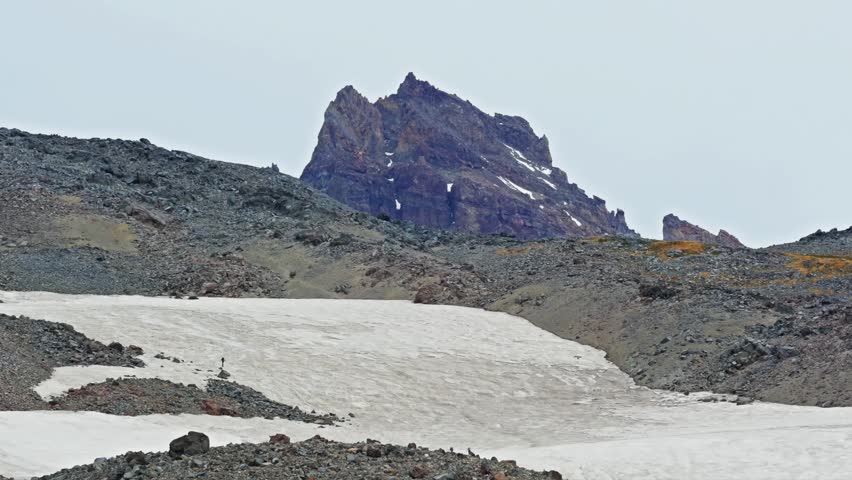 View of climbers heading towards Camp Muir on a snowfield high above Panorama Point, as seen from the Skyline Trail in Mount Rainier National Park, Washington State, USA. The rugged landscape features