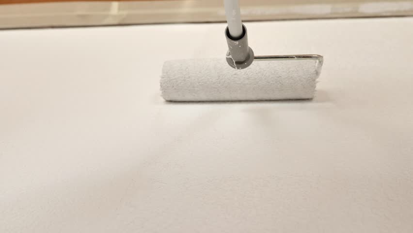 Painting walls with a roller and white paint.Interior home renovation. Close-up of a roller painting a wall white. View from below.Room cosmetic renovations. 4k footage