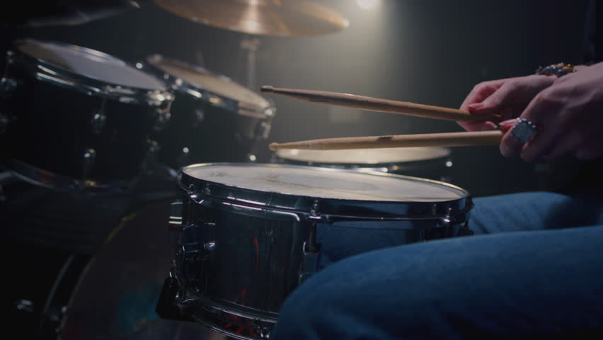 Young female drummer passionately playing a drum kit in a professional rehearsal studio, energetically striking cymbals and drums with drumsticks. Hair flying. Rock Feminist style. Woman power.