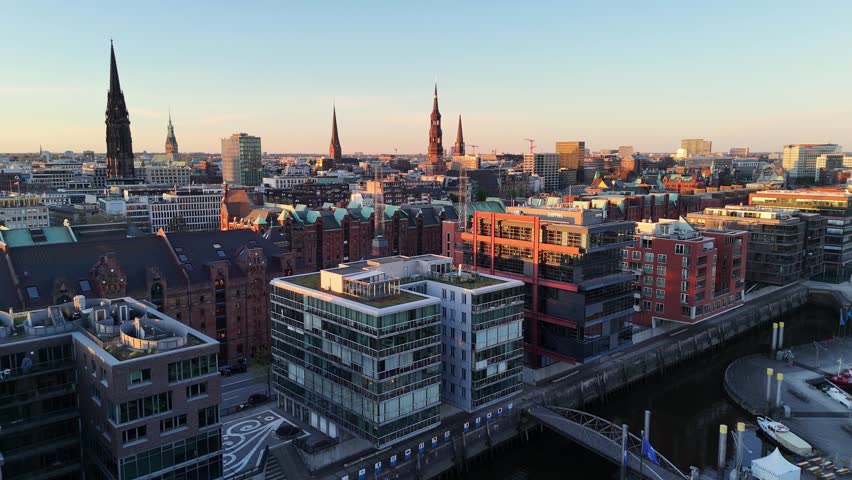 Aerial view of the historic Speicherstadt warehouses, church spires, and modern architecture during sunset in Hamburg, Hamburg, Germany.