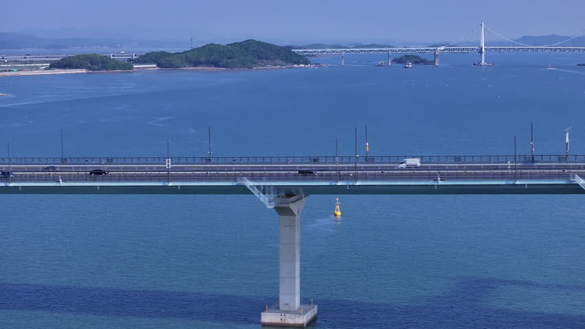 Cinematic aerial view of Cheongna Sky Bridge in Incheon, South Korea. The large cable-stayed bridge stretches across the blue sea, creating a modern coastal landscape with transportation infrastructure and ocean scenery.
