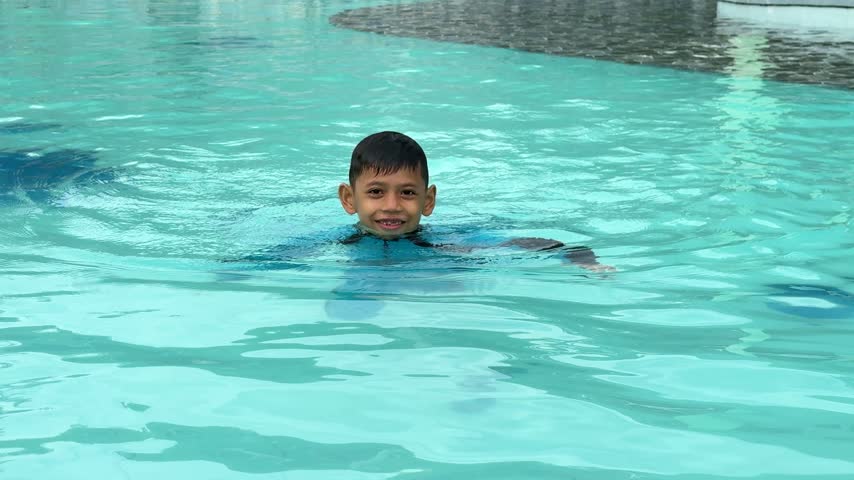 Cute and happy asian boy swimming in the swimming pool