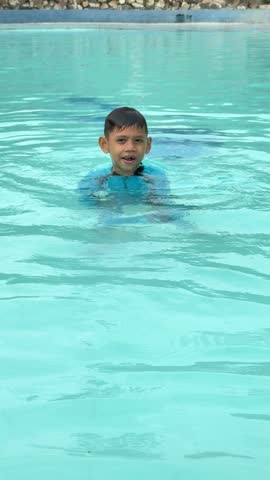 Cute and happy asian boy swimming in the swimming pool