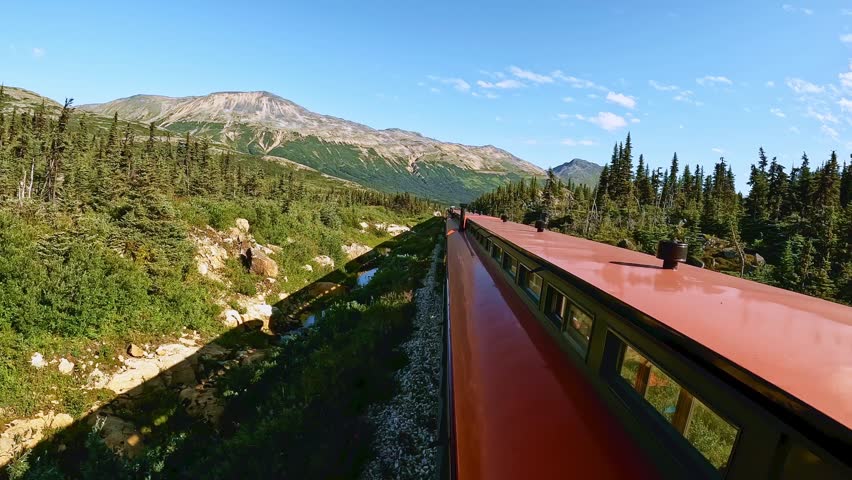 White Pass train ride between Skagway Alaska and Whitehorse Yukon Canada. Beautiful sunny day with white clouds and blue sky