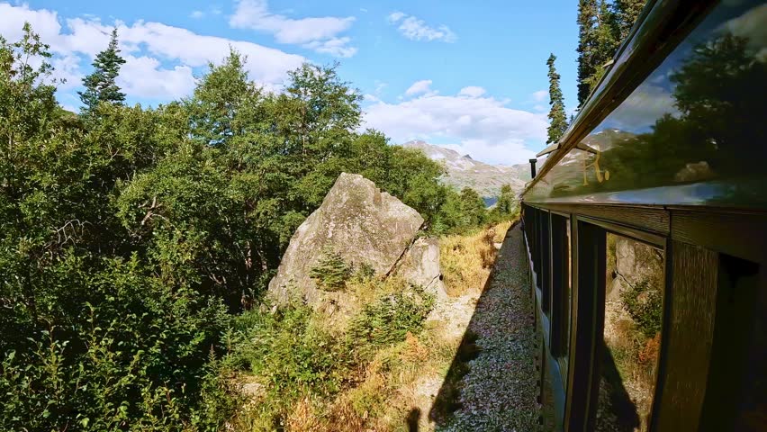 White Pass train ride between Skagway Alaska and Whitehorse Yukon Canada. Beautiful sunny day with white clouds and blue sky
