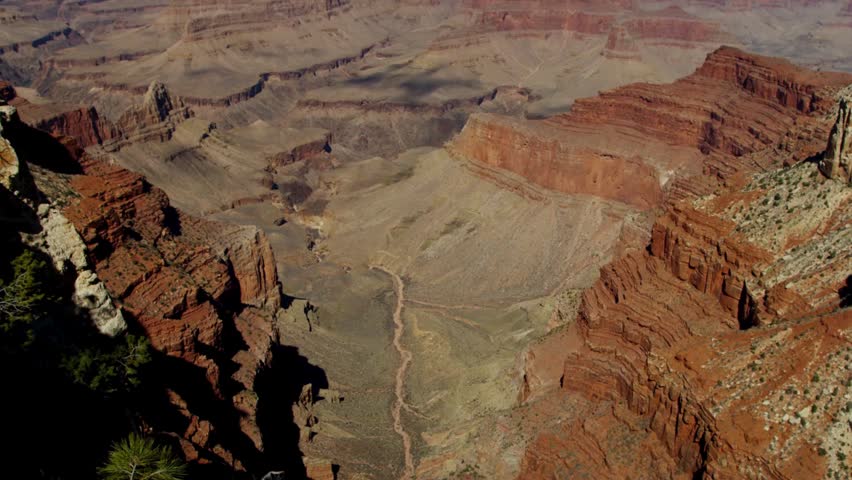 Grand Canyon National Park landscape with red rock formations and deep valleys under a clear blue sky on a bright sunny day