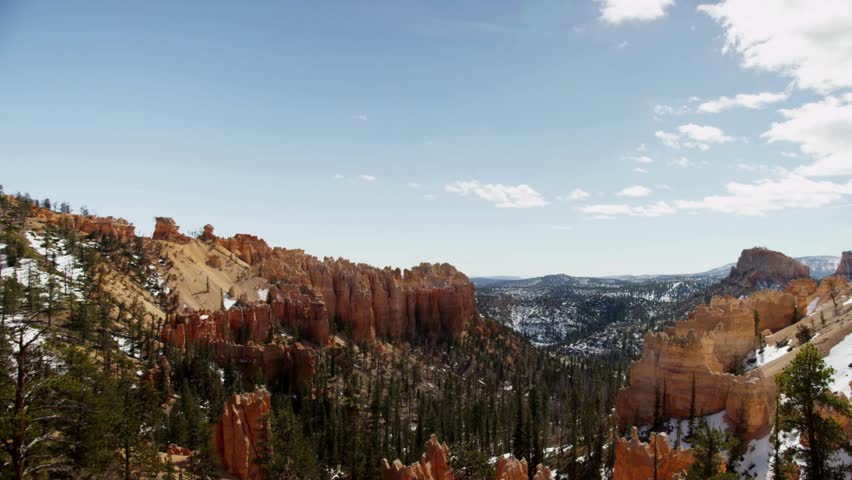 Scenic winter landscape of Bryce Canyon National Park with red rock hoodoos and green pine trees covered in snow