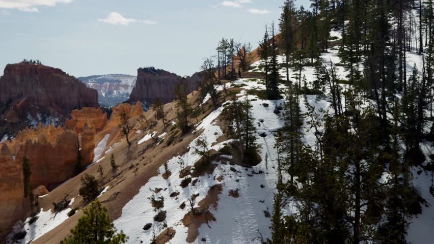 Stunning winter landscape of Bryce Canyon National Park featuring snow covered slopes and red rock hoodoos with pine trees in Utah