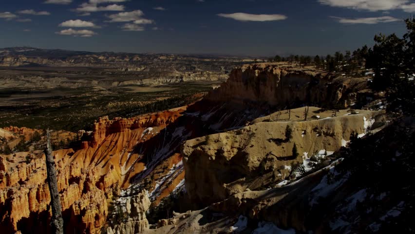 Wide aerial vista of massive Bryce Canyon National Park amphitheater showing countless red rock hoodoo formations under blue sky and clouds