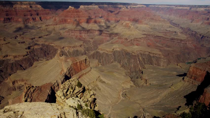 Vast panoramic landscape of Grand Canyon National Park in Arizona showing layers of red rock and cloud shadows over the deep gorge