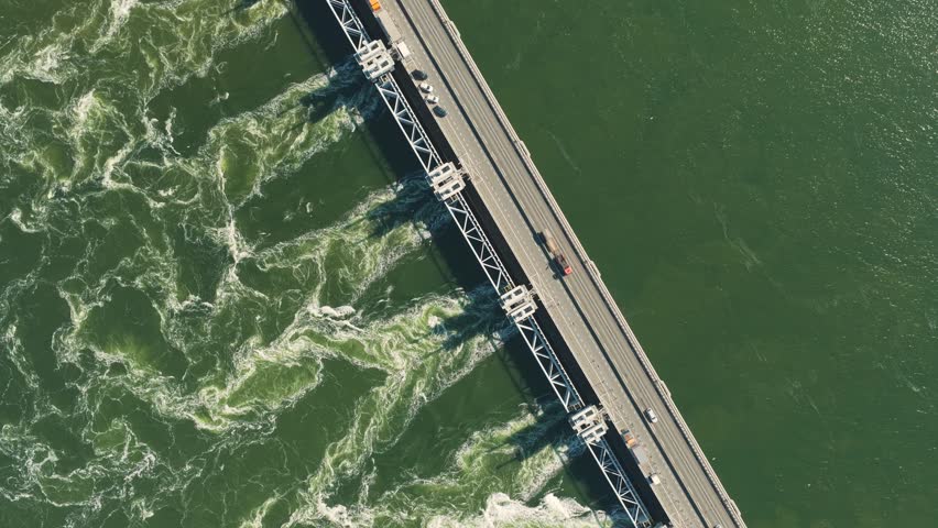 Aerial view of the Eastern Scheldt Storm Surge Barrier with water rushing through the gates and cars driving on the road in Vrouwenpolder, Zeeland, Netherlands.
