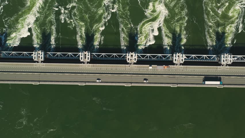 Aerial view of the Eastern Scheldt Storm Surge Barrier with rushing water and cars driving across the bridge in Vrouwenpolder, Zeeland, Netherlands.