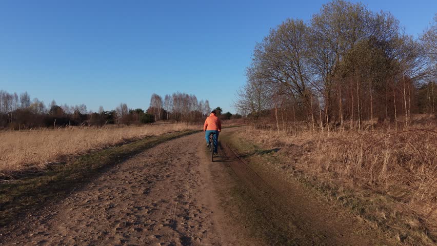 Solo rider biking along peaceful woodland dirt path